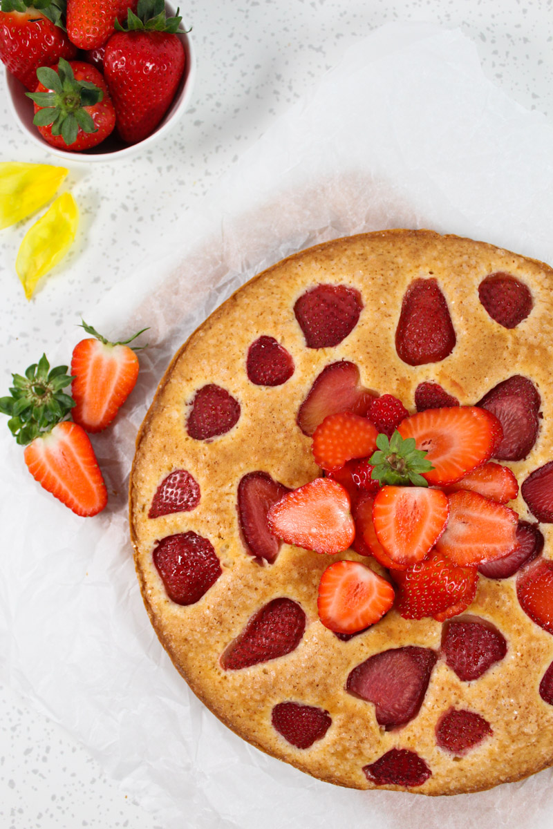 cake with strawberries on top and a small cup of strawberries behind it