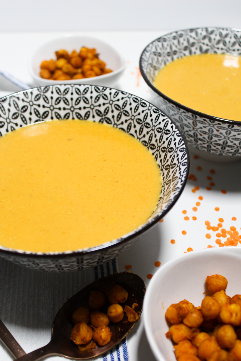 Bowls with red lentil soup and smaller bowls with chickpeas on the side