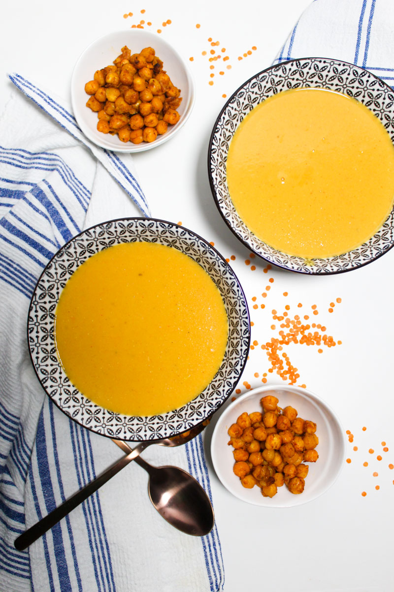 Bowls with red lentil soup. Smaller bowls with baked chickpeas on the side.